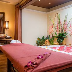 A luxurious spa room featuring a single massage bed, adorned with fresh flowers for a serene and tranquil atmosphere.