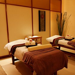 A luxurious spa room with two massage beds, each beautifully arranged with thoughtful gifts for clients, creating a welcoming and relaxing atmosphere
